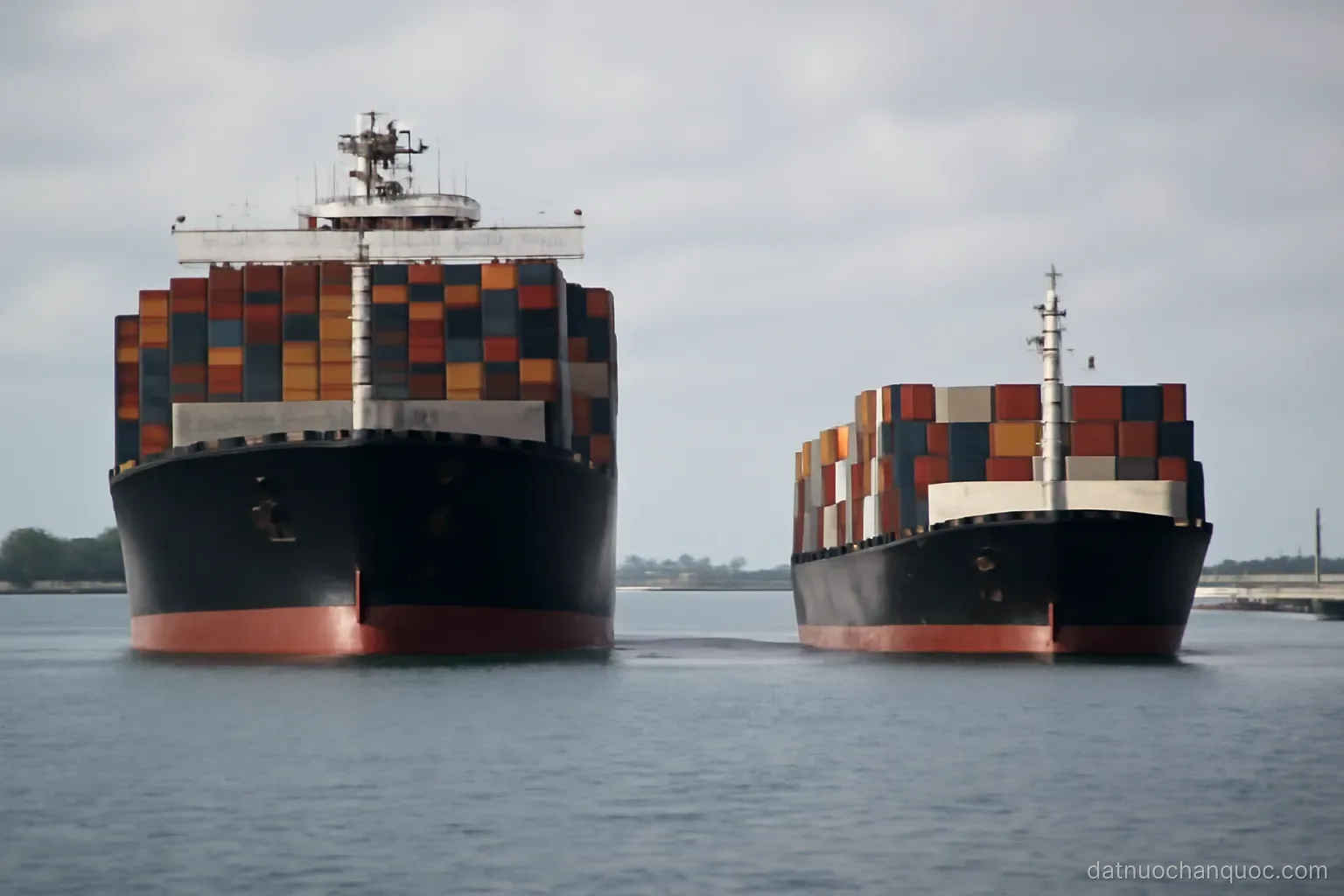 two container ships of very different sizes berthed opposite each other across a harbour basin